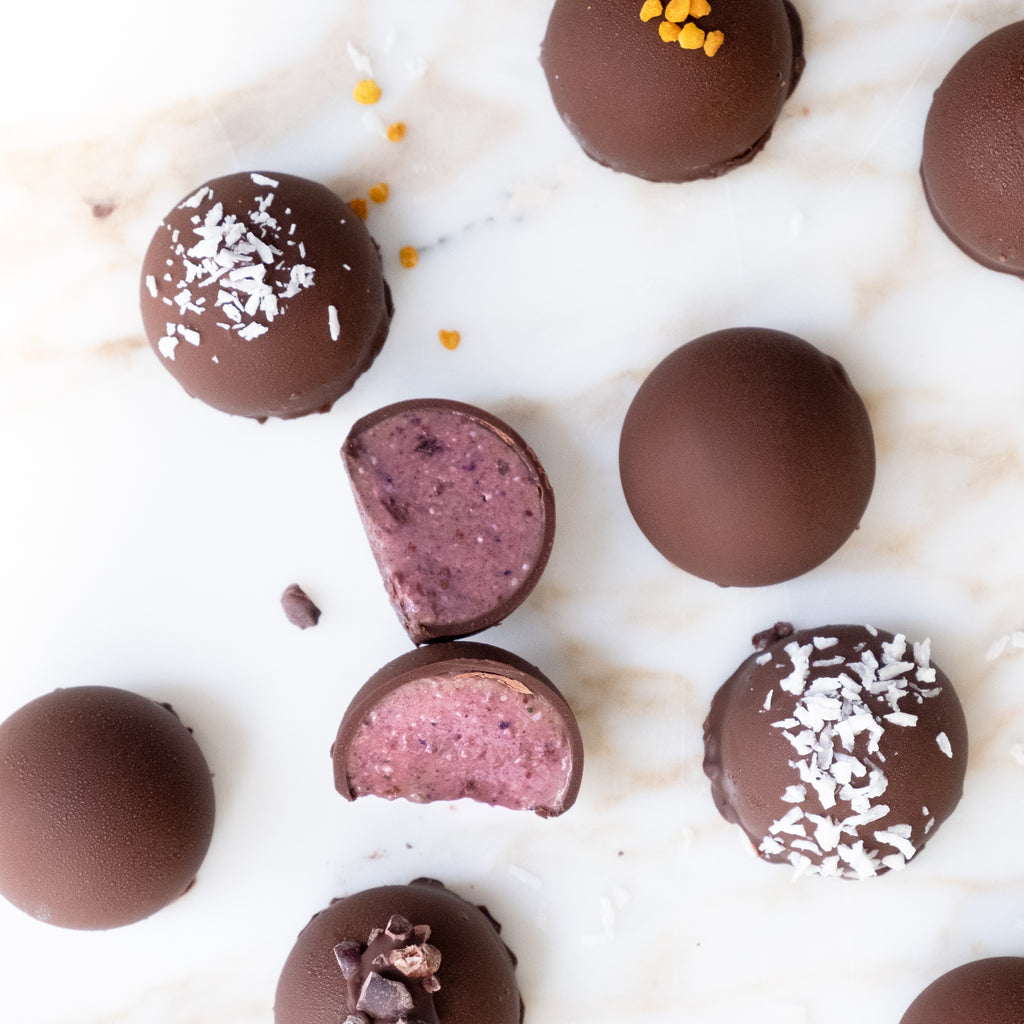 Top view of no bake acaí energy bites on white surface with coconut and bee pollen