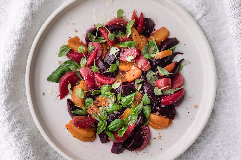 top view of beetroots salad with tomatoes and herbs on white plate