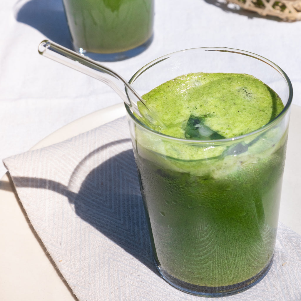 A Glass of Antioxidant-Rich Green Smoothie with a Glass Straw made with Organic Blueberry + Spinach 