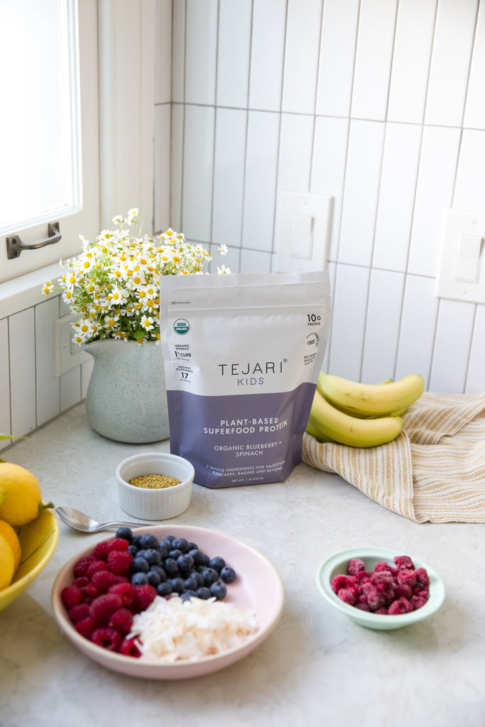 Beautiful Setting on a Kitchen Counter Top by a window. Display of Flowers, Bananas, Raspberries, Blueberries, Coconut Shavings