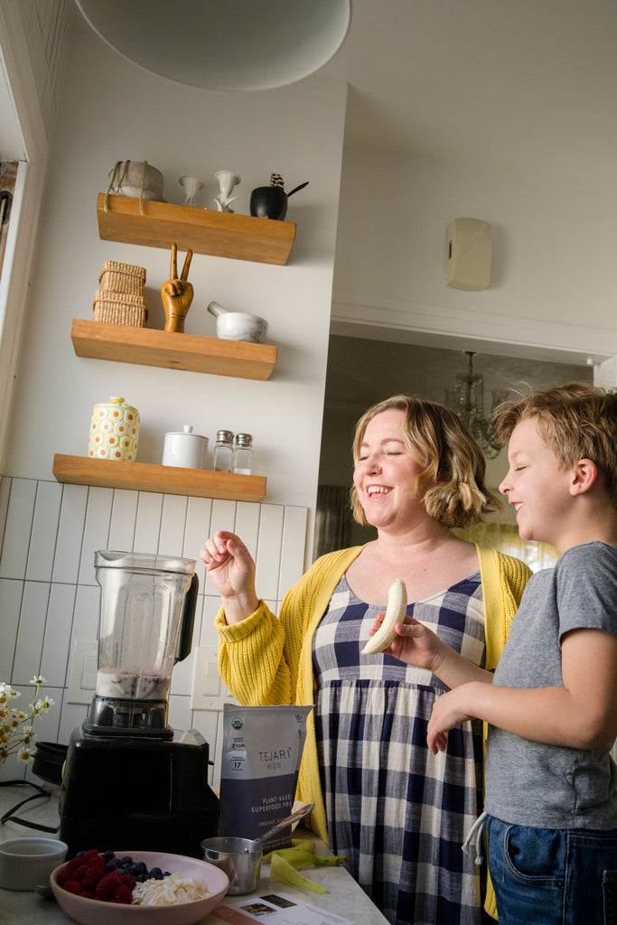 Mom and Son Enjoying Packing a Blender with Organic Blueberry + Spinach Sprinkled Package with a Variety of Ingredients Blueberries, Raspberry, Coconut Shavings, and Bananas