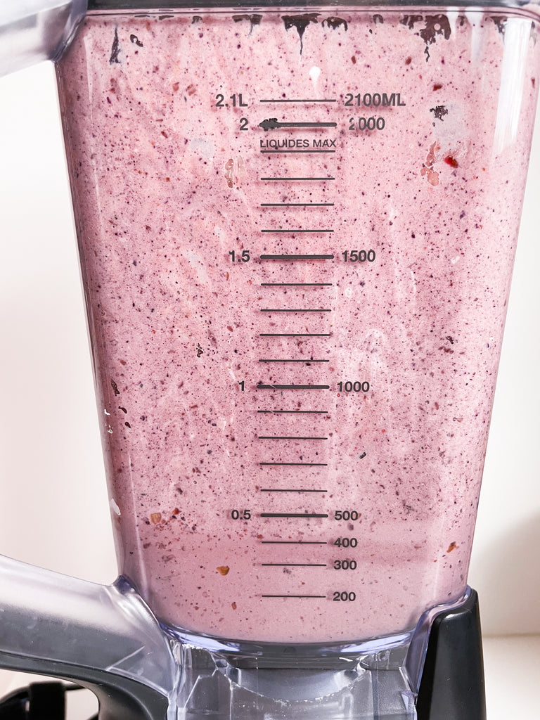 Blueberry plus spinach blend together shown in a full blender