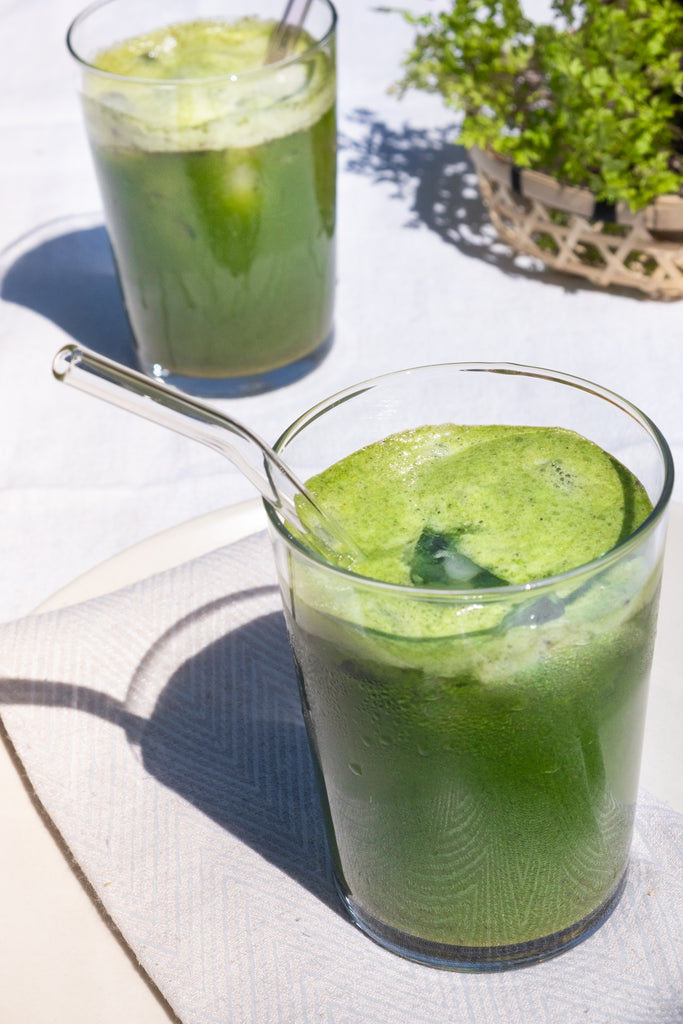 Two Glasses of Green smoothie with Glass Straws on a White Kitchen Counter Top